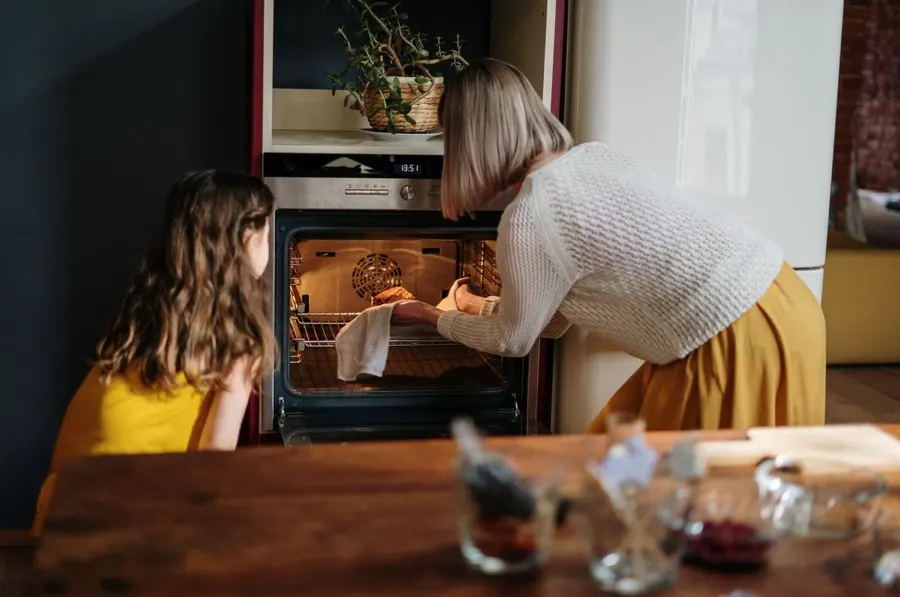 A parent and child looking into the oven together while baking at home